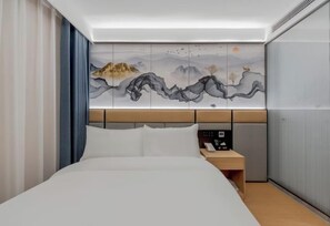 A hotel room with a bed, a nightstand, a wall-mounted artwork depicting a mountainous landscape, and a window with curtains. - YUE FEI YUN Hotel (Shanghai)