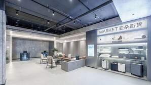 Un vestíbulo de hotel moderno con una recepción, un área de estar y una exhibición de maletas.