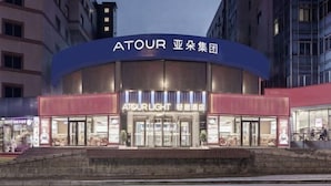 Un hotel con un letrero llamativo que dice "ATOUR" y "ATOUR LIGHT", indicando un restaurante o zona de comidas en su interior.