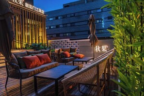 Un espacio al aire libre con sofá y sillones, una mesa y un paraguas colgante.