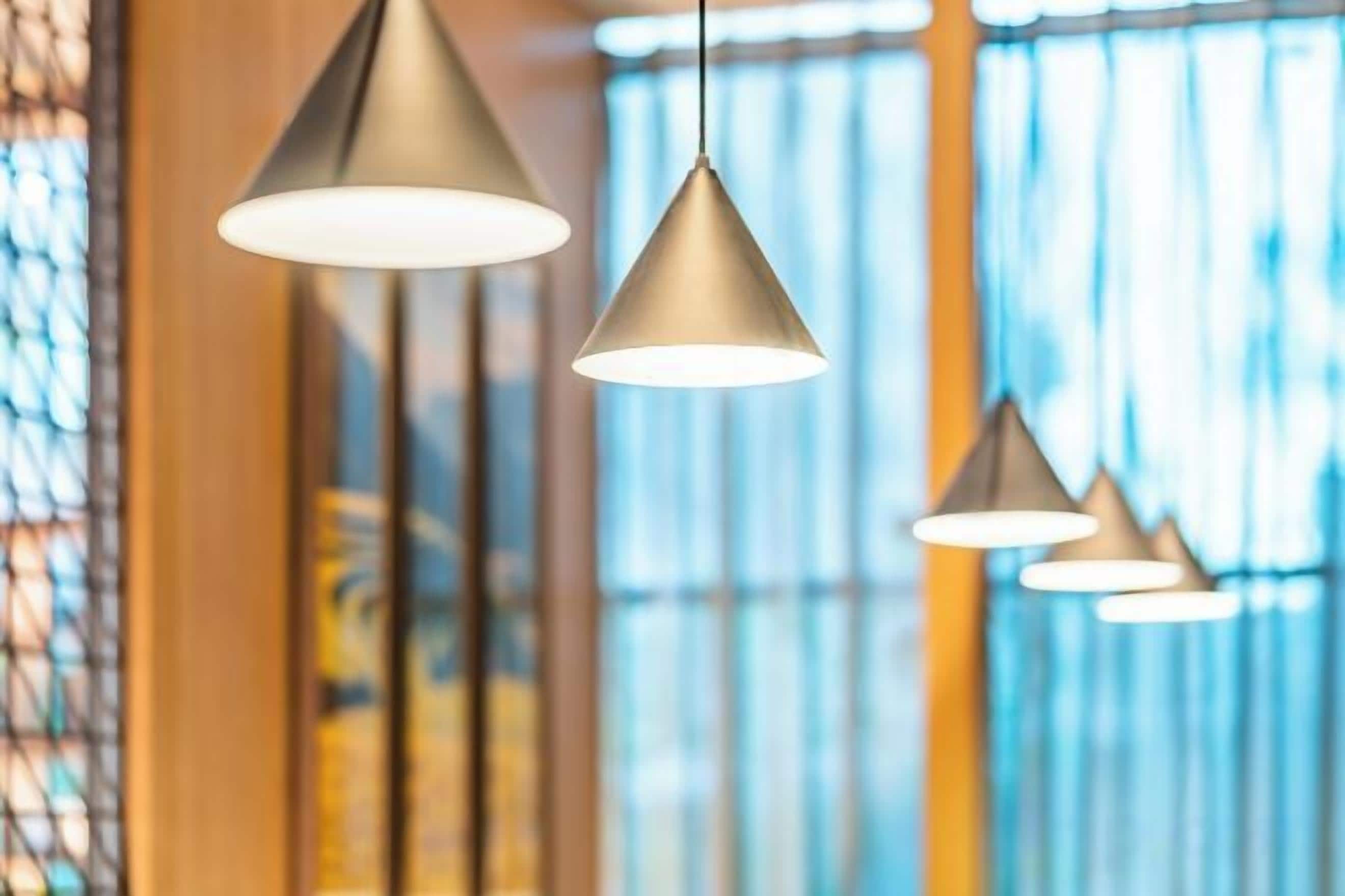A series of pendant lights hanging from the ceiling in a well-lit room with large windows.