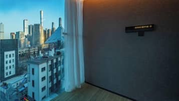 Habitación de hotel con vista panorámica de la ciudad a través de una ventana, un cartel direccional en la pared y suelo de madera.