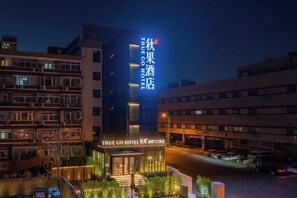Un hotel con un letrero llamativo, una entrada bien iluminada y un estacionamiento.