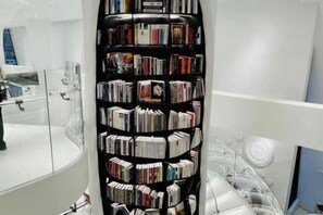 Una esquina de una habitación con una estantería negra llena de libros.