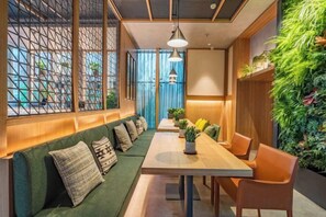 Un interior moderno con una mesa larga, asientos acolchados verdes y un jardín vertical.