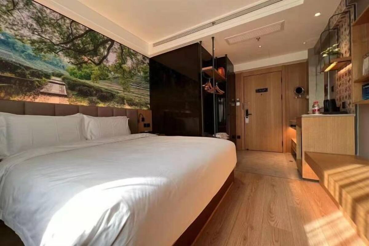 Une chambre d’hôtel moderne avec un grand lit, une fresque murale et un bureau en bois.