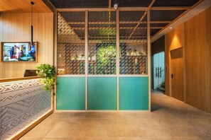 A reception area with a wooden desk, a television screen, and a green partition.