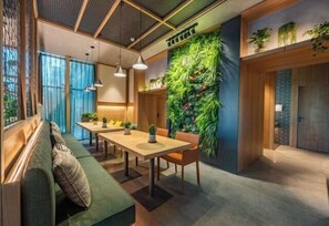Un intérieur moderne avec une longue table, des bancs et un mur végétal vertical.