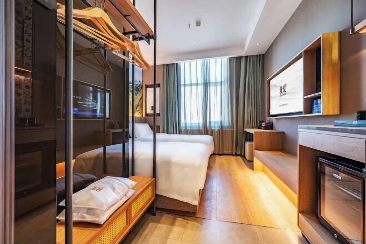 Une chambre d’hôtel avec un lit, un bureau, une télévision et une fenêtre avec des rideaux.