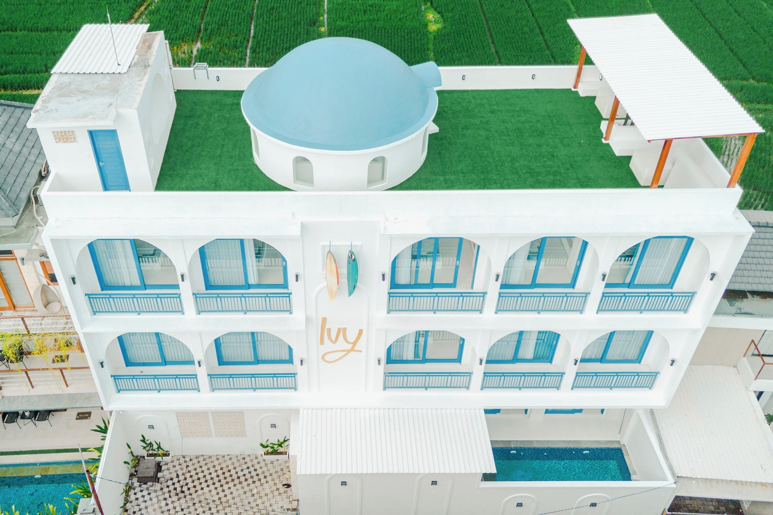 A white building with multiple balconies and a swimming pool.