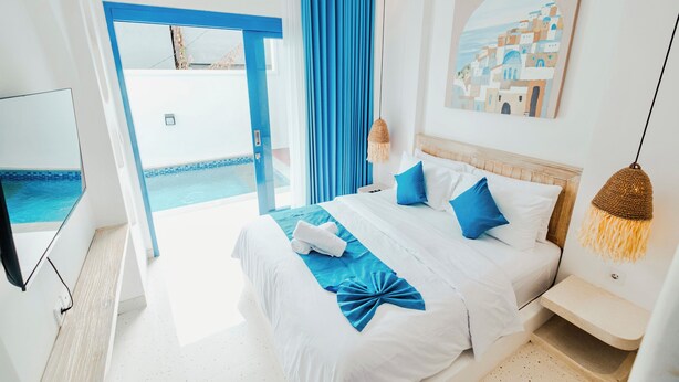 A hotel room with a bed, a TV, a painting, and a view of the pool. - Ivy Canggu (Munggu)