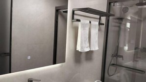 A modern bathroom with a glass shower enclosure, a towel rack with two towels, a sink, and a mirror. - Zhulian Hostel (Wenzhou)