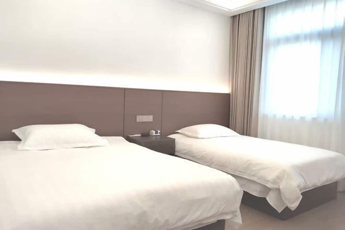 Una habitación de hotel con dos camas, una mesita de noche y una ventana con cortinas.