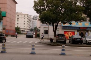 A street view with a crosswalk, parked cars, and buildings with signage. - Zhulian Hostel (Wenzhou)