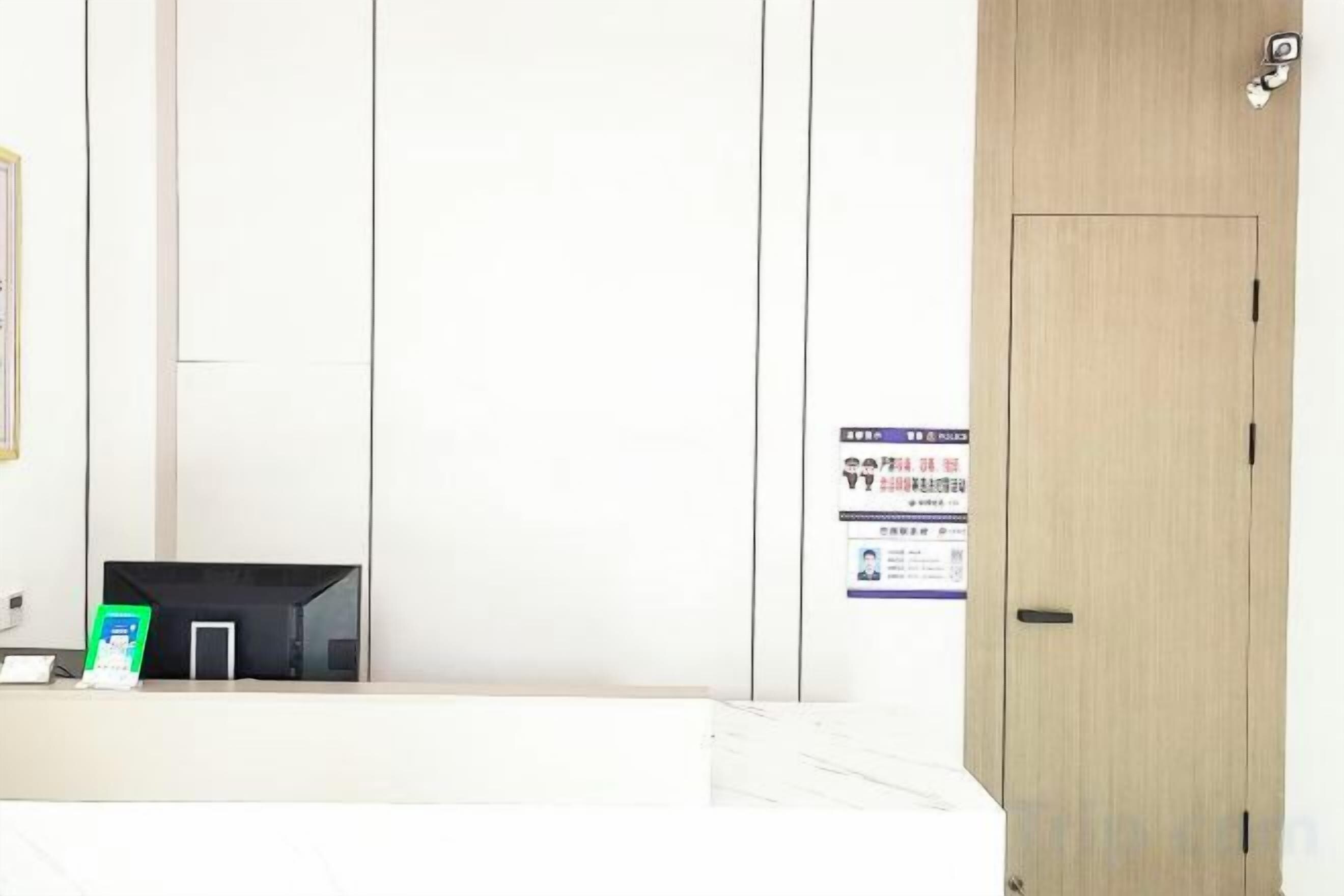 A hotel room with a wooden door, a reception desk, and a poster on the wall.