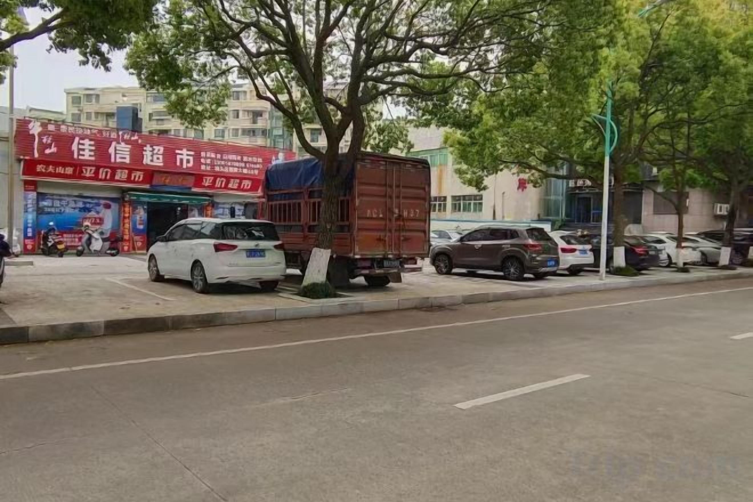 A street scene with parked cars, a delivery truck, and a building with a red sign.