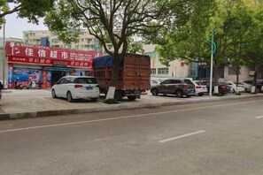 A street scene with parked cars, a delivery truck, and a building with a red sign. - Zhulian Hostel (Wenzhou)