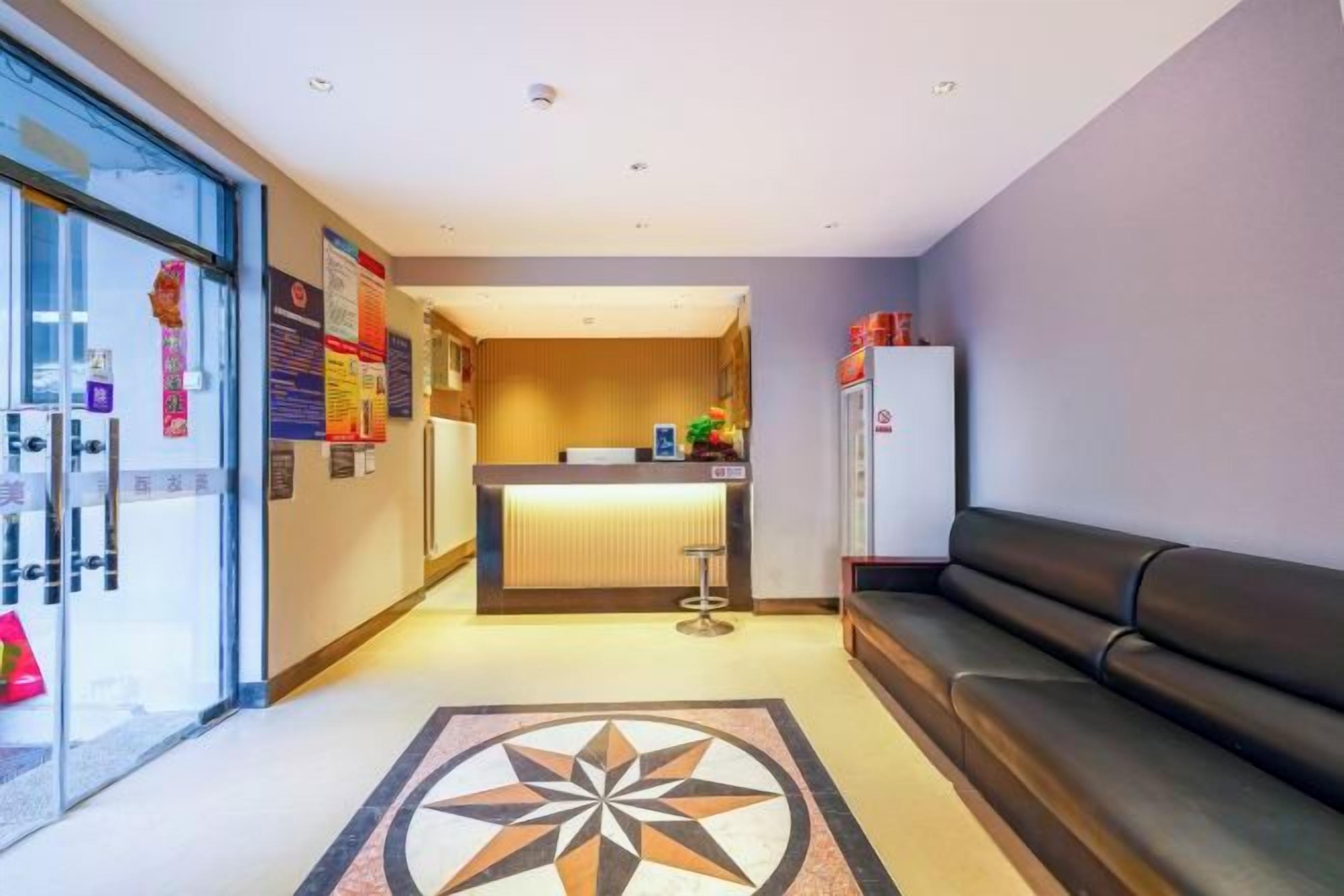 Um saguão de hotel com balcão de atendimento, área de estar e piso estampado.