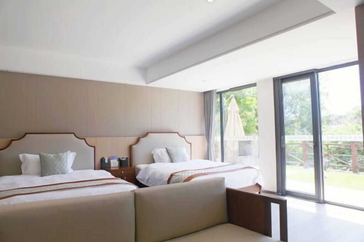 A hotel room with two beds, a large window, and a balcony.