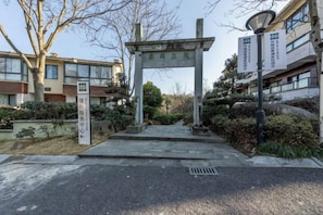 Una puerta de piedra con un cartel, un camino empedrado y un edificio al fondo.