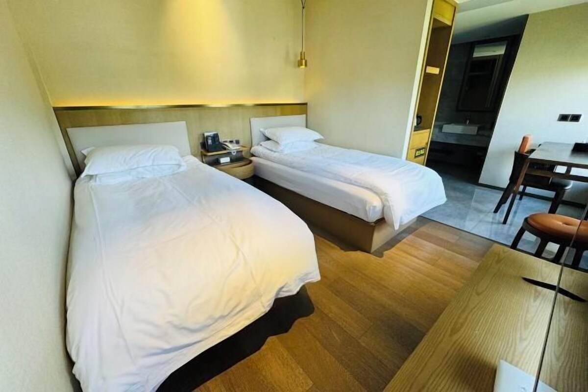 Ein Hotelzimmer mit zwei Einzelbetten, einem Holztisch und einem kleinen Tisch.