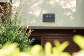 A building with a wooden door and a sign above it. - Banmeiju GINLAN JIA Vacation Apartment (Jiande)