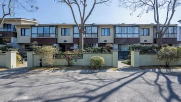 A row of townhouses with a paved driveway and landscaped areas.
