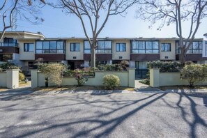 A row of townhouses with a paved driveway and landscaped areas.