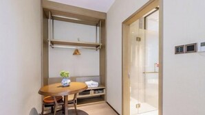 A compact room with a wooden table, a bench, and a small potted plant. There is a sliding door with a glass panel and a wall-mounted control panel. - Banmeiju GINLAN JIA Vacation Apartment (Jiande)