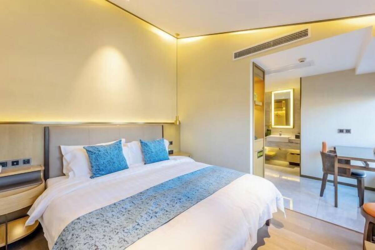 A hotel room with a bed, bedside table, and a view of the bathroom.