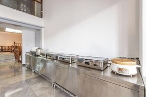 A buffet setup with stainless steel appliances and a coffee maker.