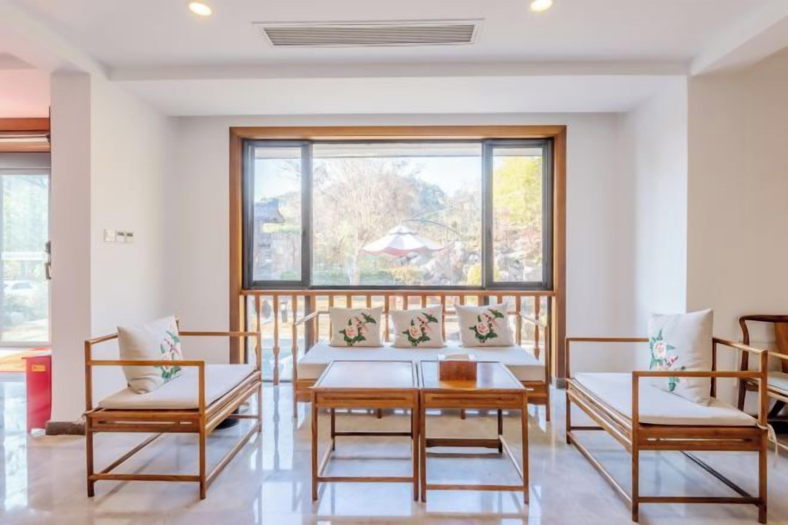 A modern interior with a large window, wooden furniture, and a view of the outdoors.