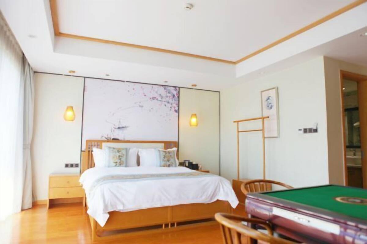 A hotel room with a wooden bed, a green pool table, and a large abstract painting on the wall.