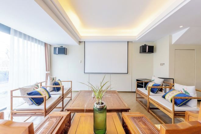 A hotel room with a large bed, two bedside tables, a wooden coffee table, and a projector screen.