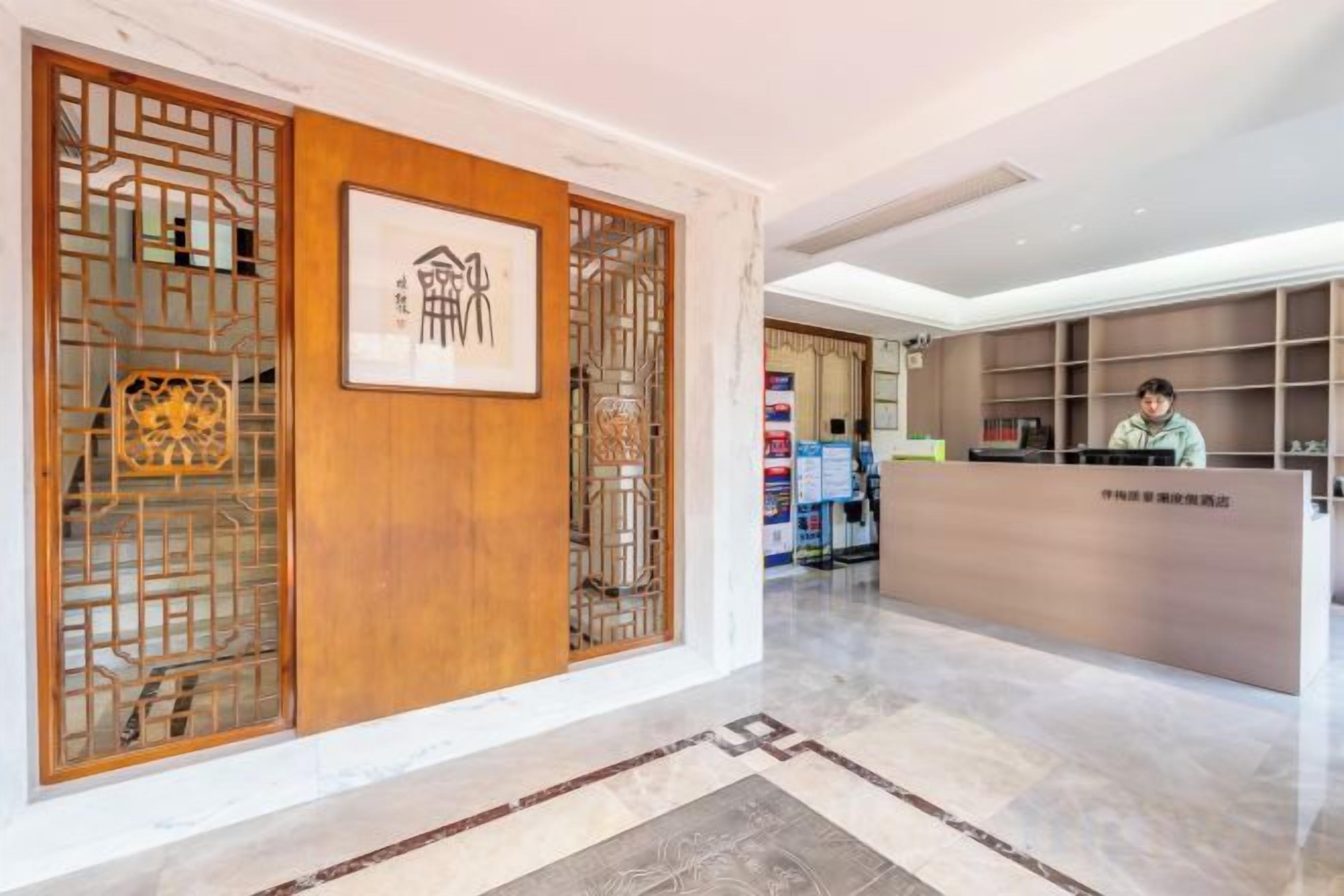 A reception area with a wooden partition, a reception desk, and a person seated behind it.