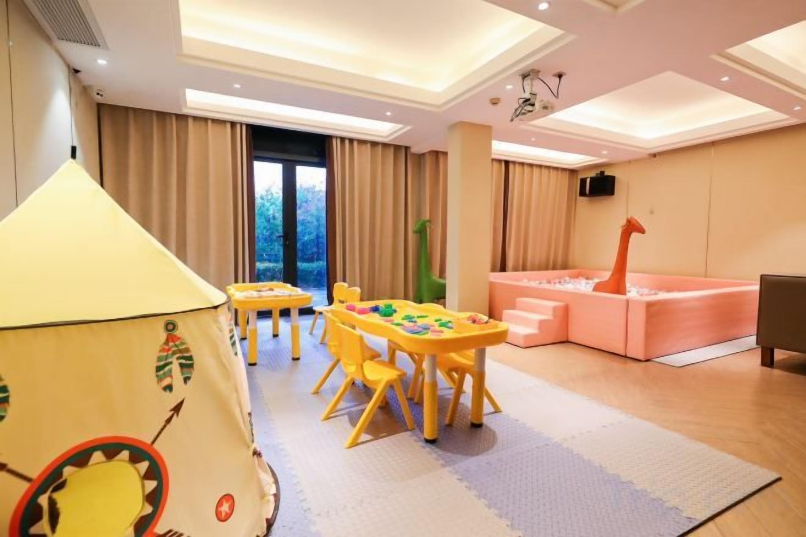 A children's play area with a table, chairs, and a tent. There is a sofa and a television in the background.