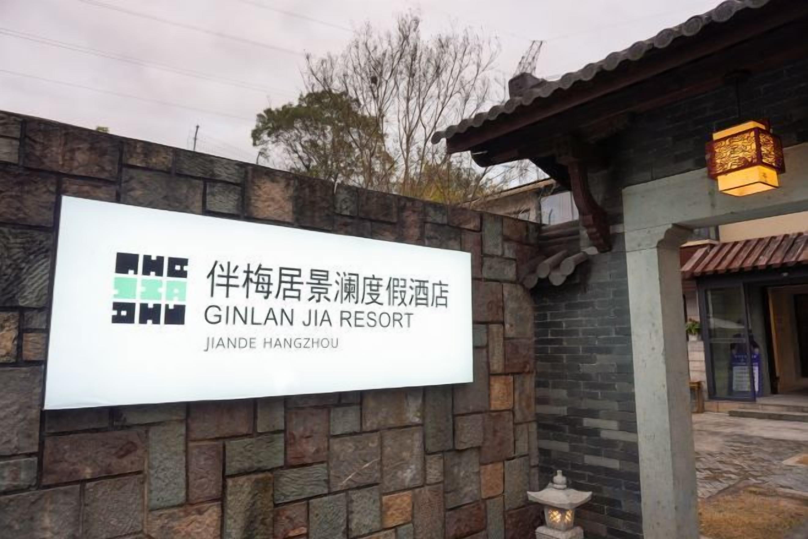 Cartell del Jinlan Jia Resort, amb mur de maó i elements arquitectònics xinesos tradicionals.