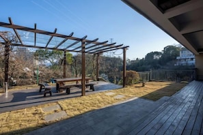 Un patio al aire libre con pérgola, mobiliario y vistas del paisaje circundante.