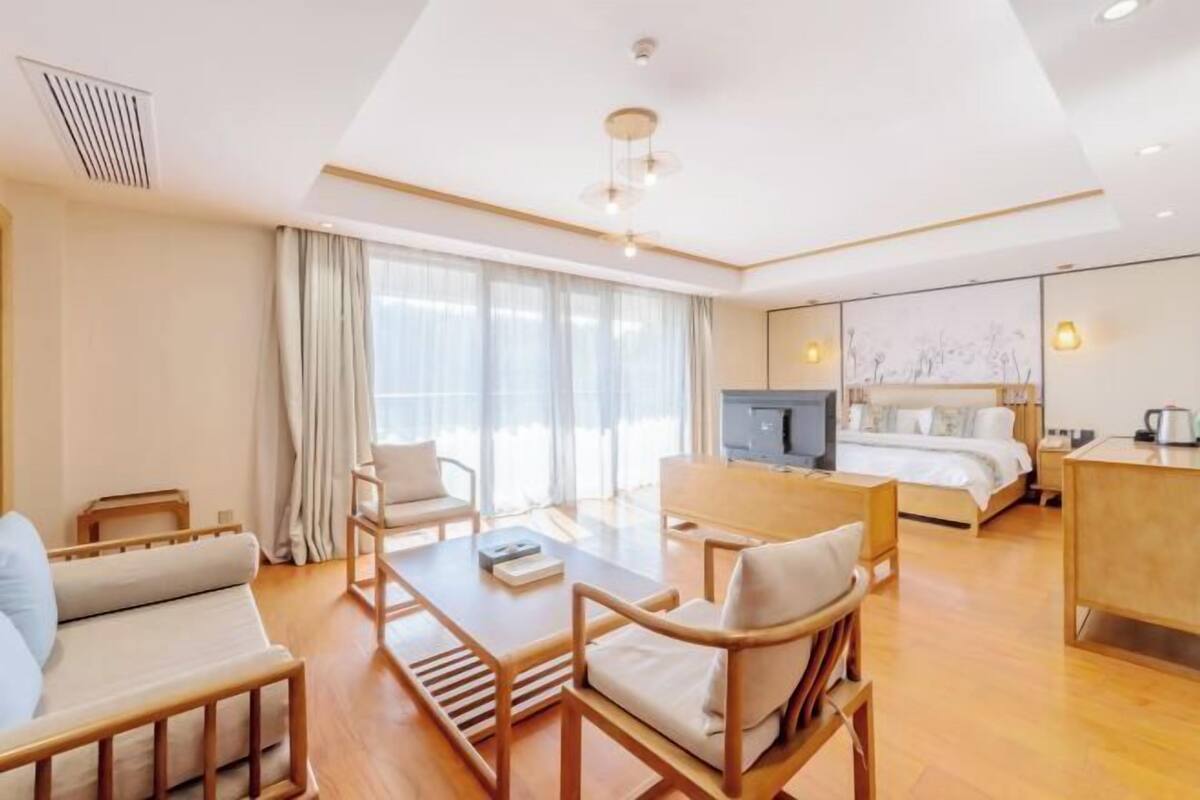 A hotel room with a bed, a desk, a sofa, and a dining table.