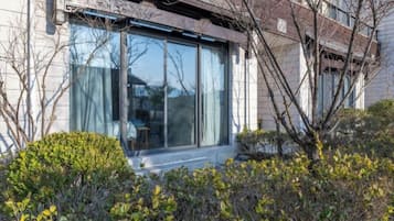 Un edificio moderno con amplios ventanales, un espacio exterior para sentarse y un jardín cuidado.
