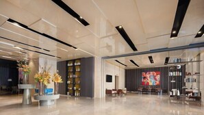 A spacious lobby with a modern design, featuring a central seating area, a large abstract painting, and a bookshelf. - Wanda Yue,Huaian Hongze Lake (Huai'an)