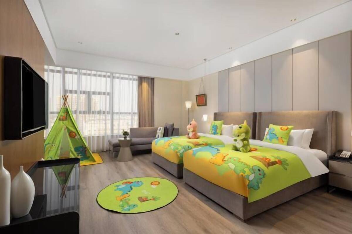 Habitación de hotel con dos camas, un sofá, un televisor y una ventana con cortinas.