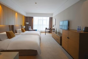 Hotellihuone, jossa on kaksi sänkyä, työpöytä, televisio ja vaatekaappi.