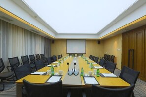 A conference room with a long table, chairs, a projector screen, and a whiteboard.