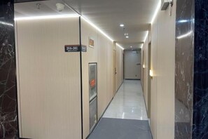 A hotel corridor with a sign indicating room number 301-2001, a reception area, and a marble wall on the right. - Yakelai Hostel (Shanghai)