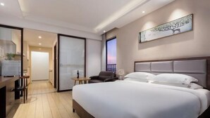 Una camera d'albergo con un letto grande, una scrivania con una sedia, un tavolino e un quadro appeso al muro.