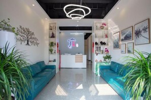 A modern lobby with teal sofas, a reception desk, and a ceiling light fixture.
