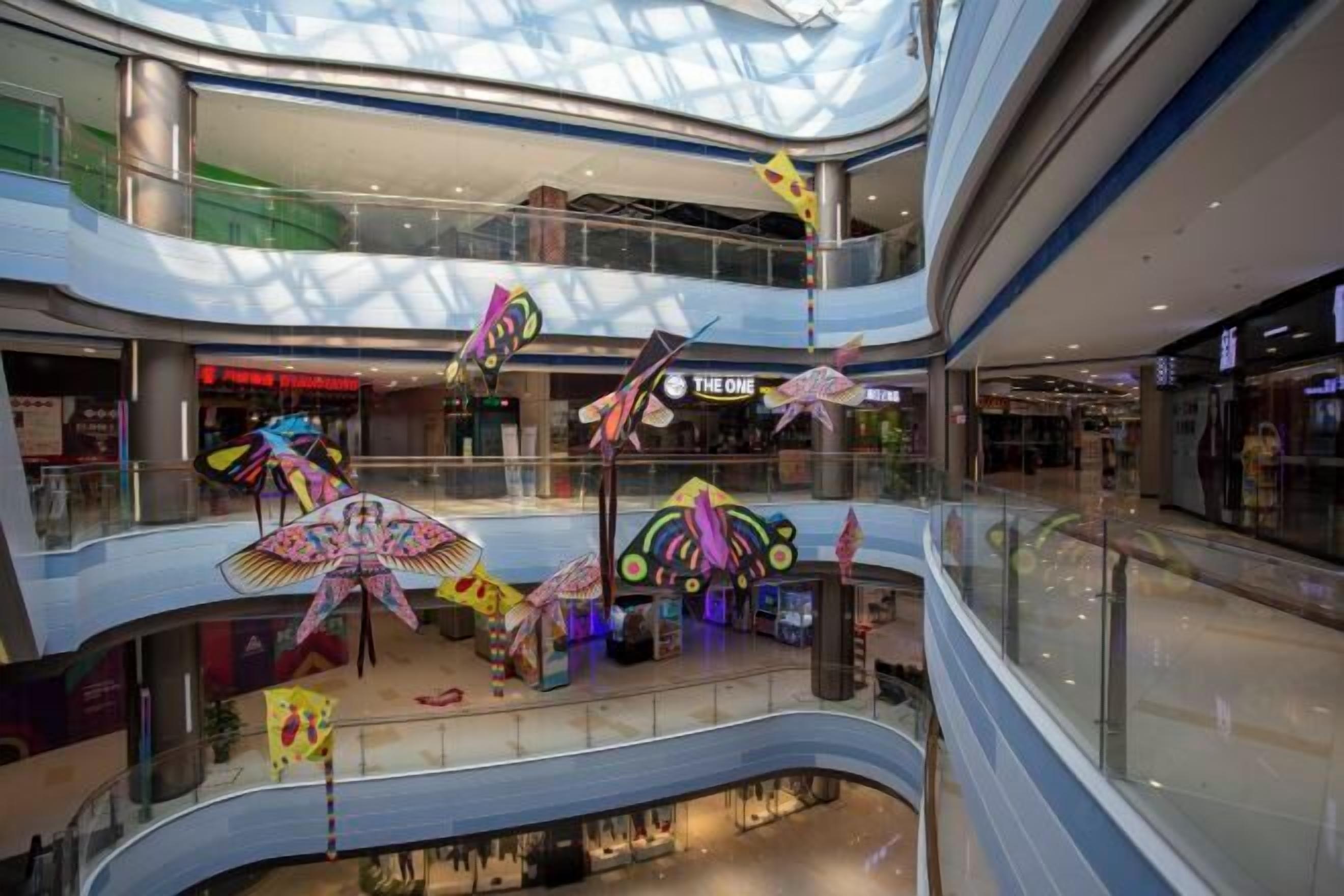 A multi-level shopping mall with glass railings and various stores on each floor.