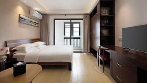 Una camera d'albergo con un letto, comodino, televisore, armadio e vista sul balcone.