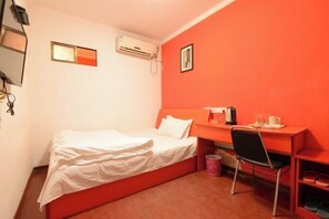 A single bed with white bedding, a desk with a chair, a small trash bin, and a picture on the wall. - Jiye Hostel (Zhenjiang)